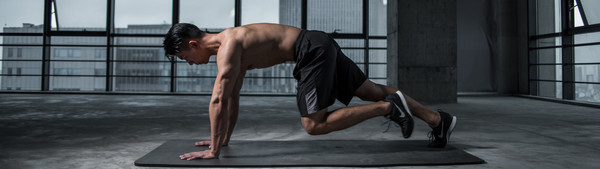 athletic man in a open gym performing moutain climbers on a yoga mat